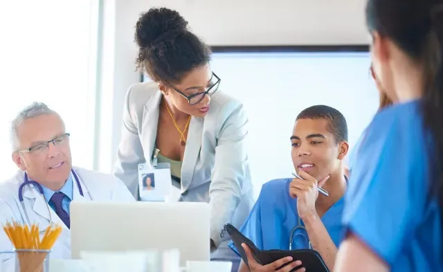 Nurse administrator speaking with other healthcare managers during team meeting